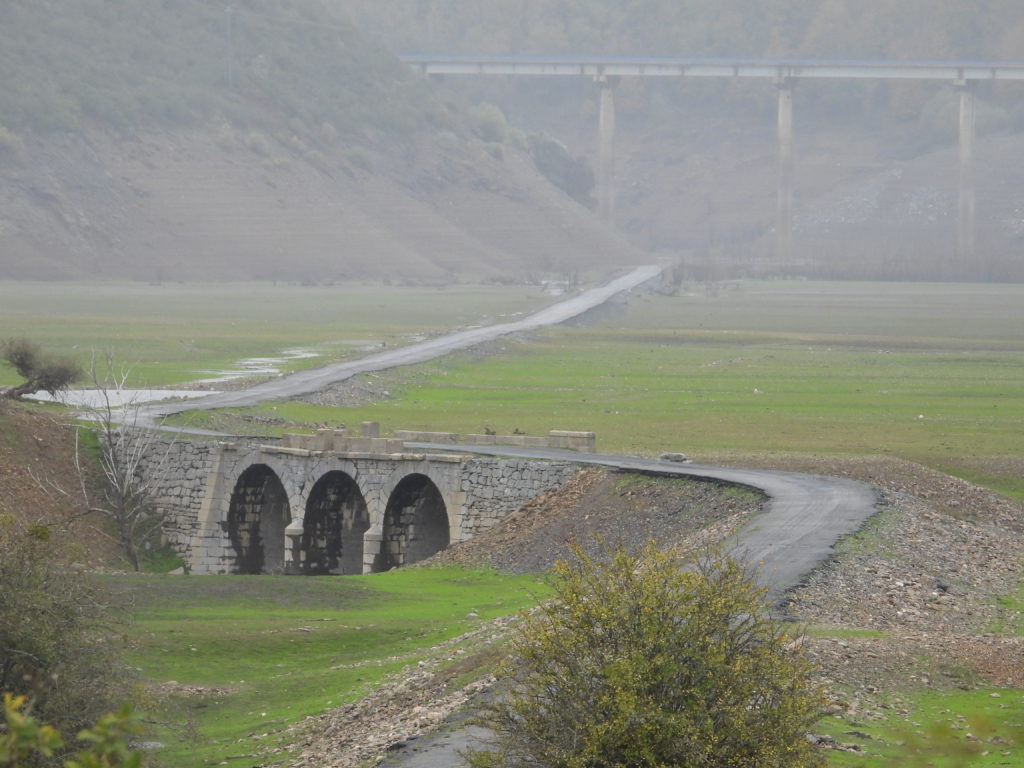 Abandoned Stone arch bridge and road normally under water 