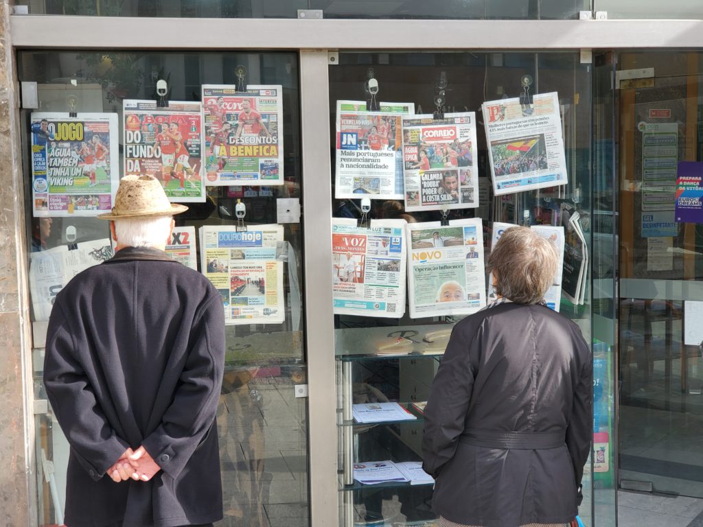 These two are absorbed in reading the sports headlines posted in a gaming store window.