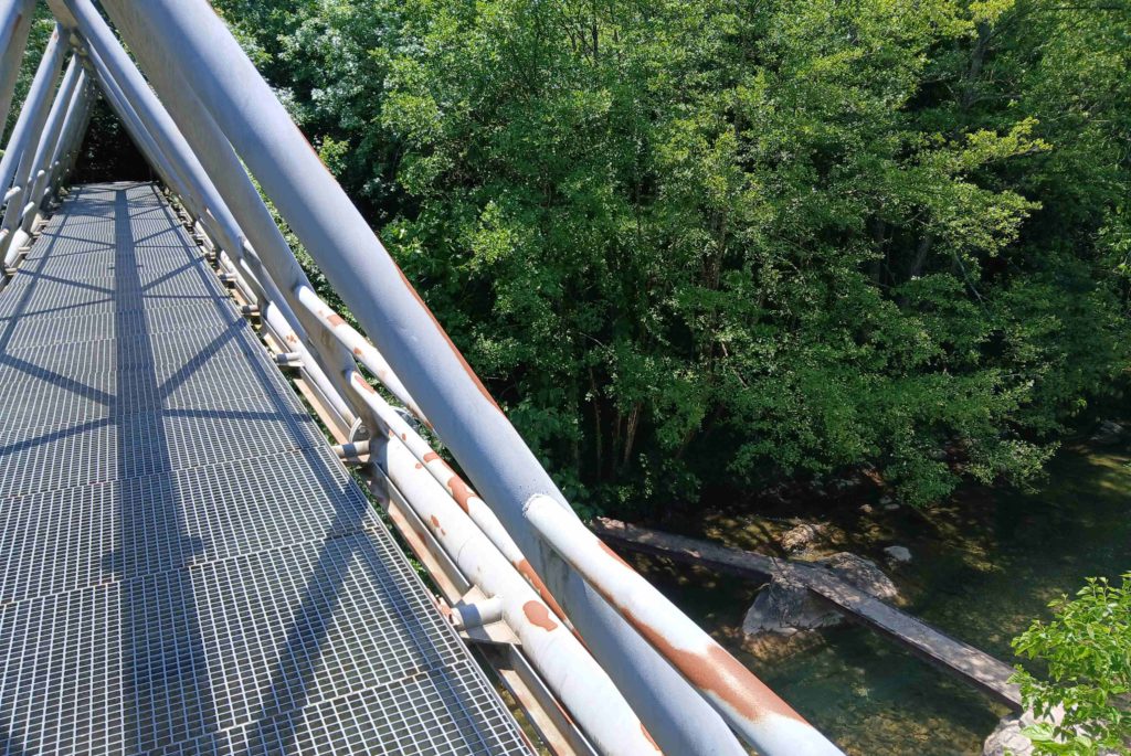 Technology contrast. The modern, steel footbridge over the stream and the simple one far below.
