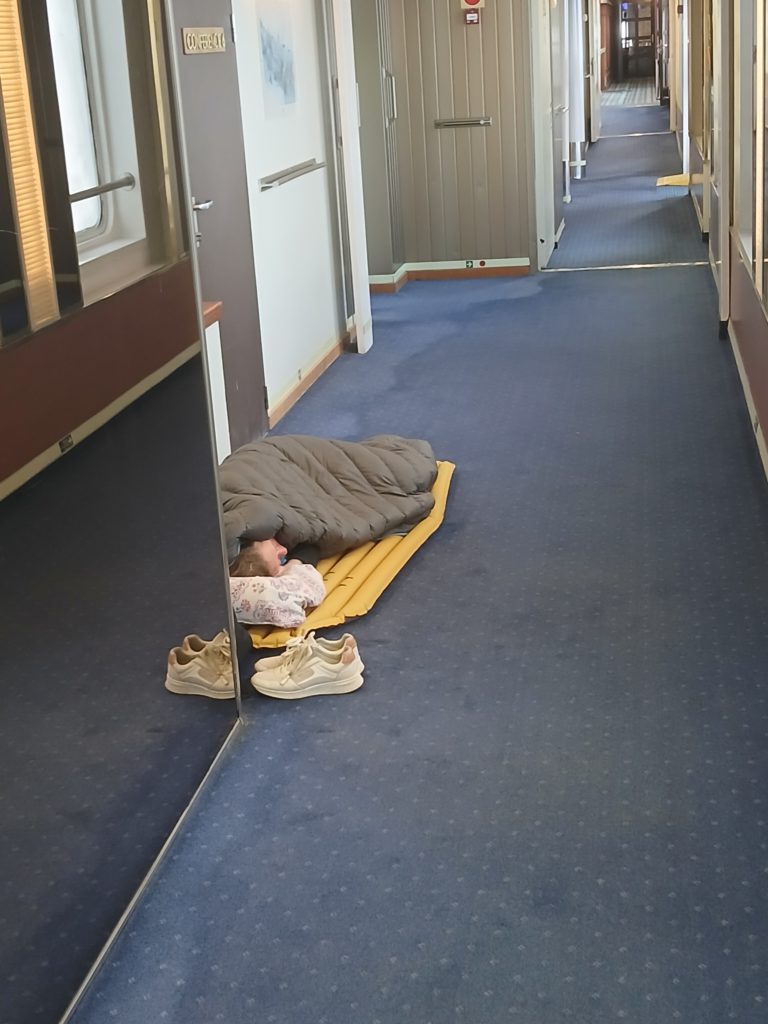 These people must know the ropes. They have a bag and pad but chose the hallway as a bedroom.